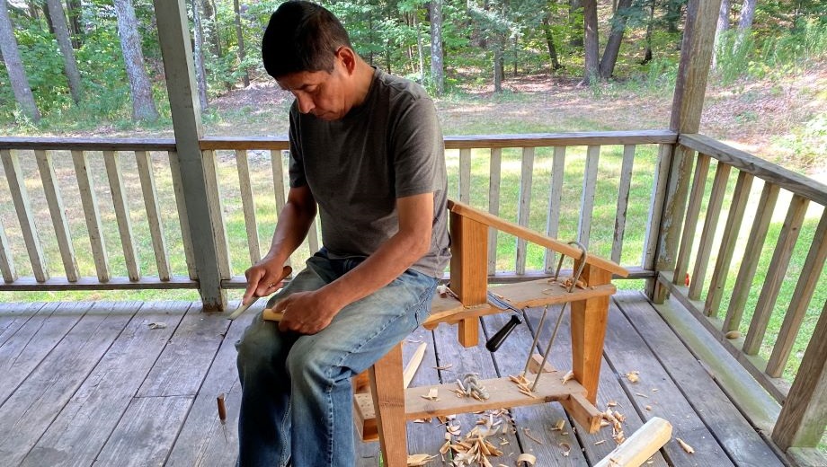 Artist woodworking while sitting outside on deck