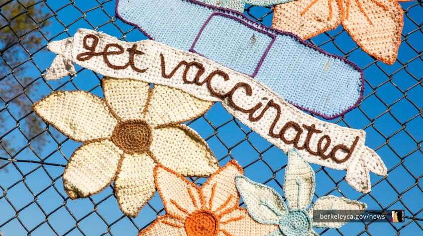 Yarn knitting on outdoor fence saying "get vaccinated"
