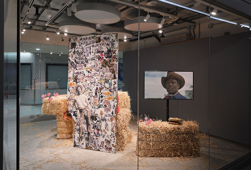 Hay bales surrounding a collage and video projection of a Black cowboys