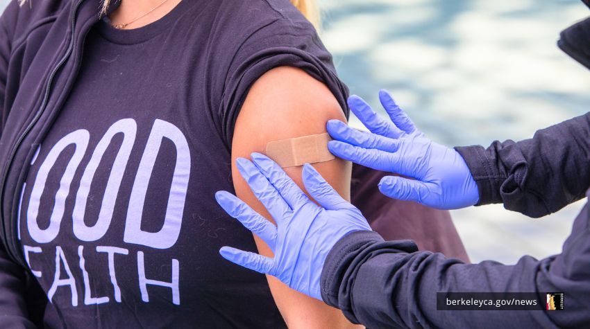Gloved hands applying a bandaid to a person's arm