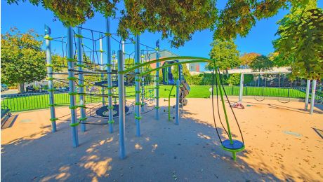 Blue and green outdoor metal playground on a sunny day.