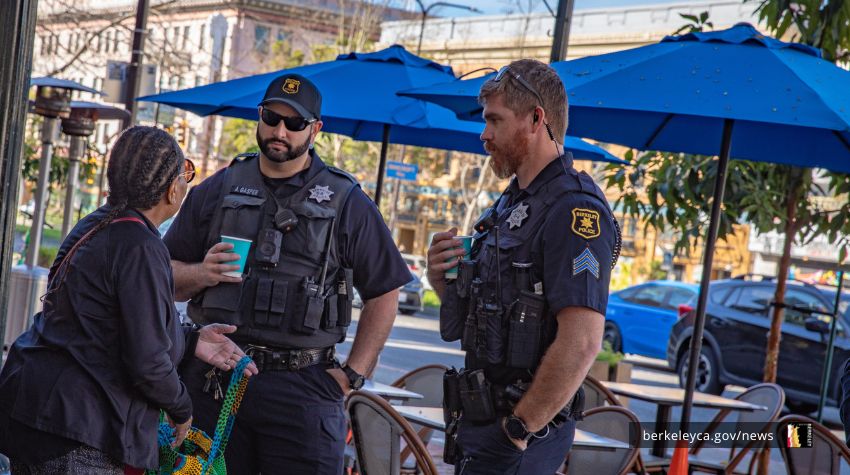 Two Berkeley Police officers talk to a civilian at a Coffee with a Cop event