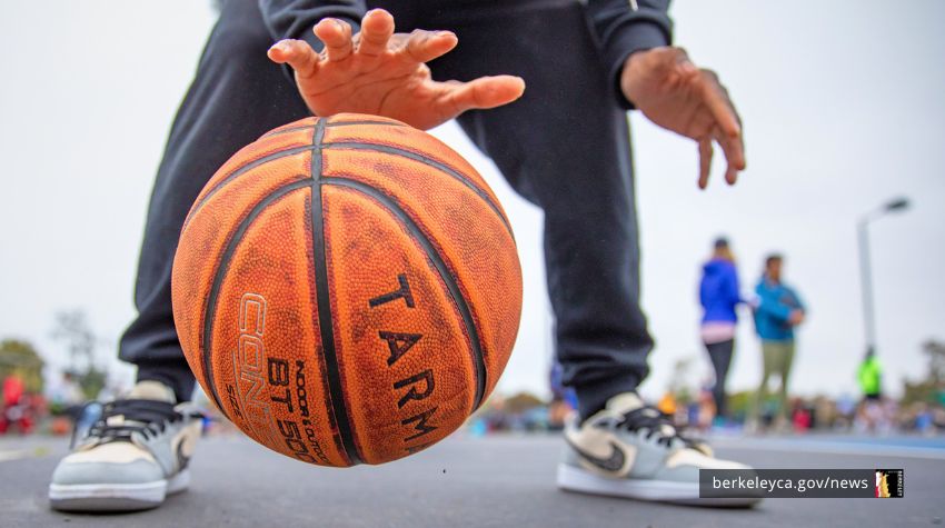 Child dribbles basketball on outdoor court. 