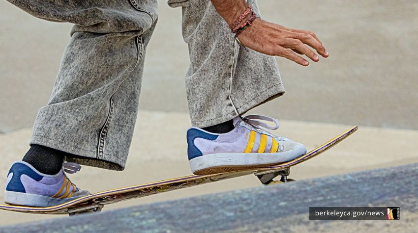 Closeup of a person's feet and hand while leaning low while on a skateboard.
