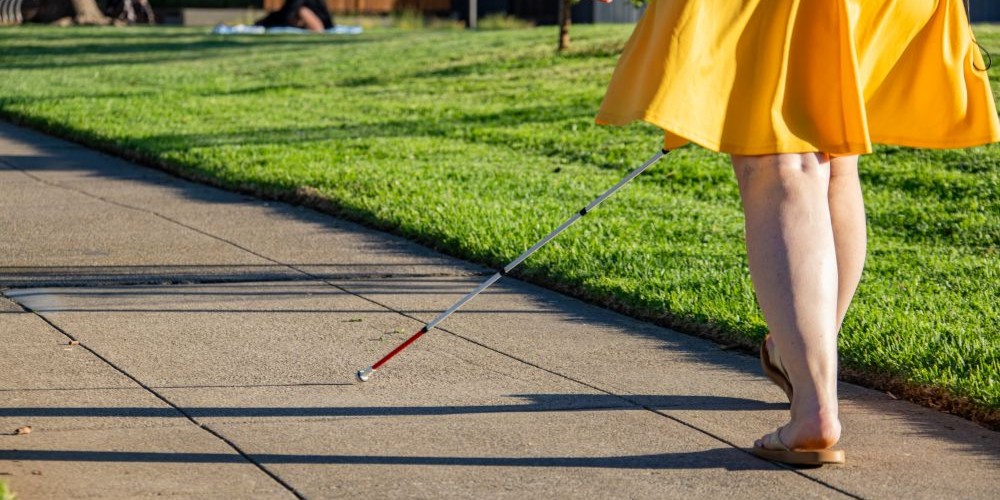 Person using a cane to navigate a sidewalk