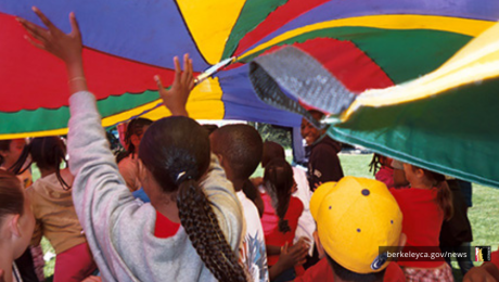 Kids play under parachute at Community Picnic