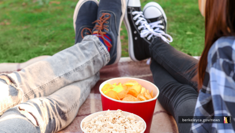 People seated on the ground with popcorn and chips
