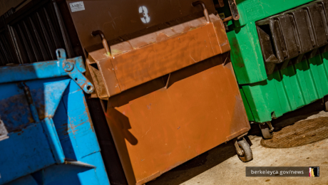 Three large dumpsters, that are blue, brown, and green in color. 
