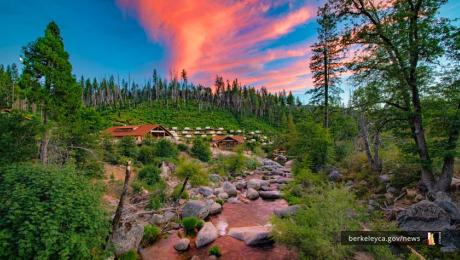 Sunset over trees, cabins, and river