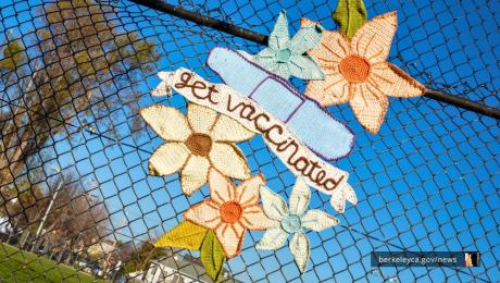 Yarn art with flowers, bandage, and banner reading "get vaccinated"