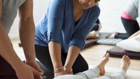 Massage therapy class with a participant and instructor working on a student’s leg.