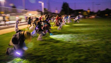Kids run with flashlights through field, searching for eggs.