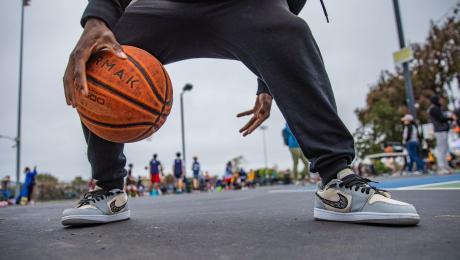 Person dribbling a basketball between their legs