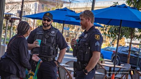 Two Berkeley Police officers talk to a civilian at a Coffee with a Cop event