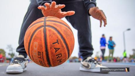 Child dribbles basketball on outdoor court. 
