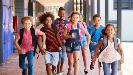 elementary school children running with backpacks on