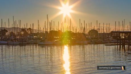 Sunrise over the Berkeley Marina, with sailboats silhouetted against the sky and sunlight reflecting across the water.