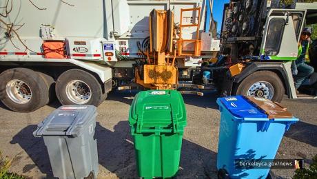Trash, compost, and recycling carts lined up in front of a collection truck.