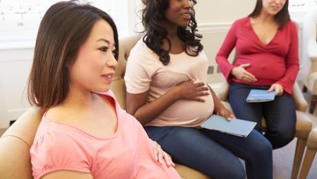 Diverse group of pregnant people gathered together in a supportive prenatal setting.