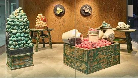 ceramic fruit sit in a clear gallery case.