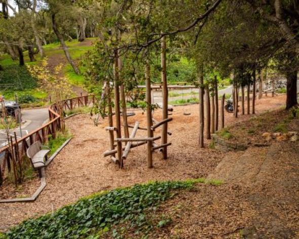 New John Hinkel Playground with play structure and bench from hillside view